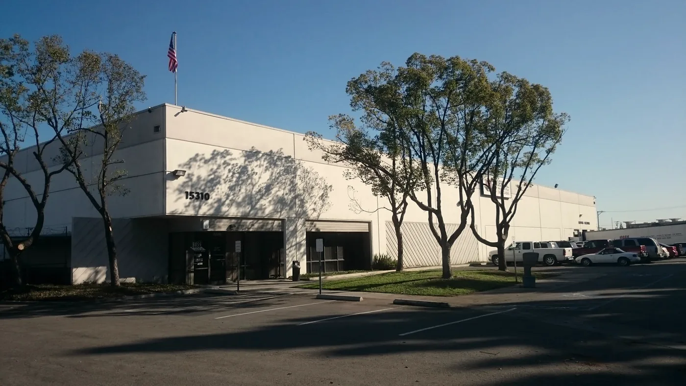 A single-story Ross Bindery production facility, with a flag at the roofline and staff parking along the front elevation.